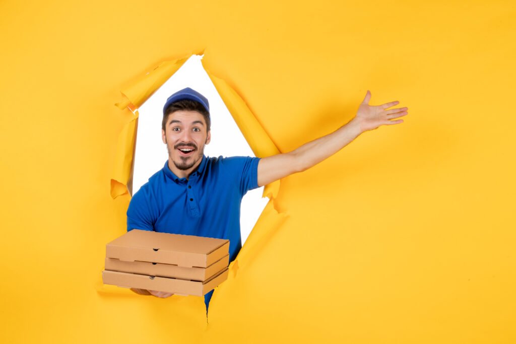 front-view-male-courier-holding-pizza-boxes-yellow-space-scaled